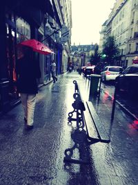 Rear view of man riding bicycle on road in rainy season
