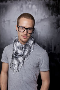 Portrait of young man standing against wall