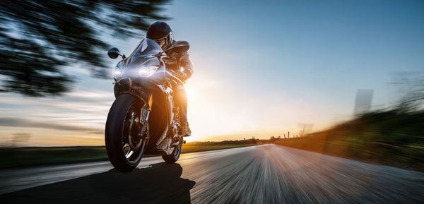 Man riding motorcycle on road against sky