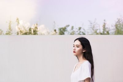 Young woman standing against wall