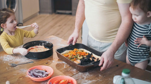 Home made child kid preparing ffod bake with parent help to father