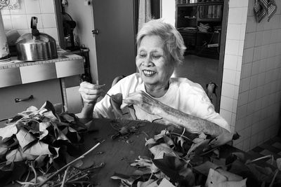 Senior woman holding dried leaf at table