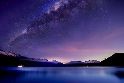 Scenic view of lake and mountains against sky at night