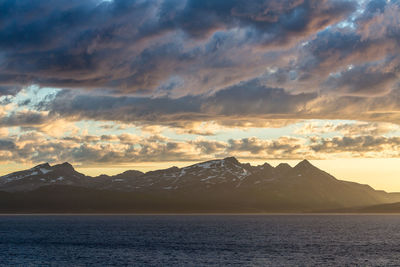 Scenic view of sea by mountains against sky during sunset