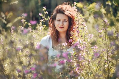 Portrait of beautiful young woman against pink flowering plants
