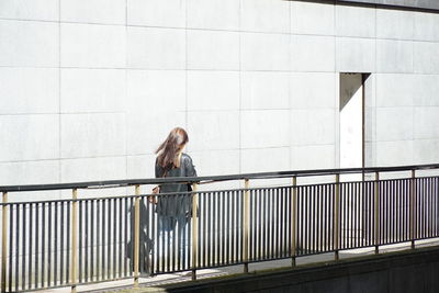 Side view of person against railing against wall