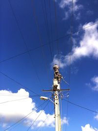 Low angle view of electricity pylon against blue sky