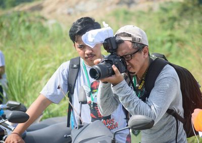 Young man holding camera outdoors