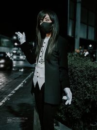 Woman standing against wall at night