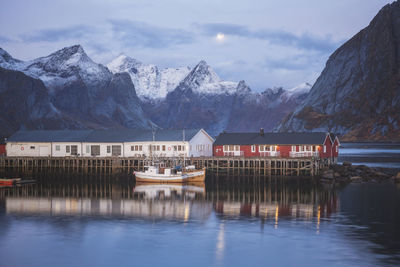 Houses by snowcapped mountains against sky during winter