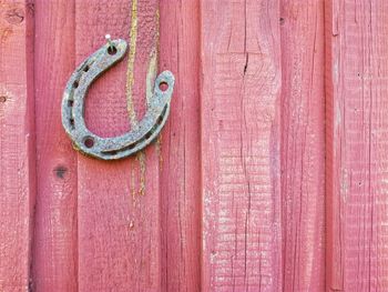 Close-up of horse shoe hanging on red wooden door