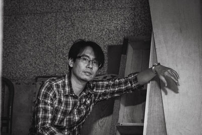 Portrait of young man standing against wall at factory 