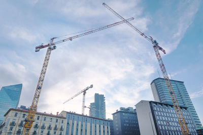 Low angle view of cranes against sky