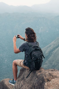 Rear view of woman photographing on mountain