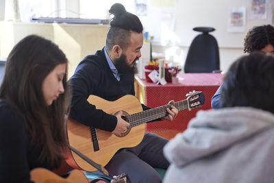 Teenagers attending guitar lesson