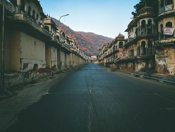 Empty road amidst buildings against sky