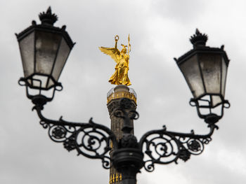 Low angle view of cross on street light against sky