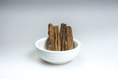 Close-up of bread in bowl on table against white background