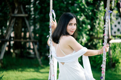 Portrait of woman sitting on swing at park