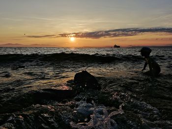 Boy playing in sea against sky