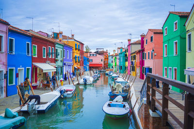 Boats moored in canal amidst buildings in city