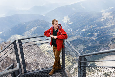 Portrait of man standing on railing against mountains