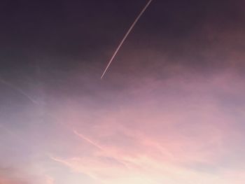 Low angle view of vapor trail in sky during sunset