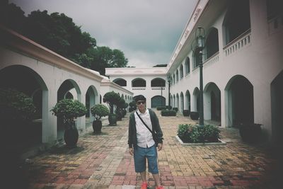 Portrait of young man standing by building