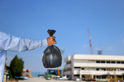 Man holding umbrella against clear blue sky