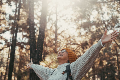 Side view of woman standing against trees