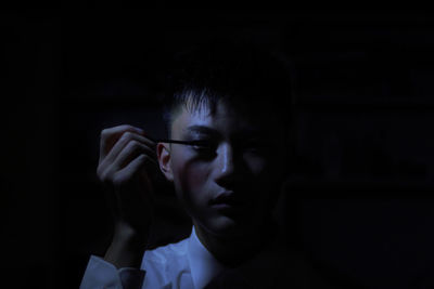 Man applying mascara in darkroom