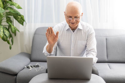 Senior man waving during video call at home