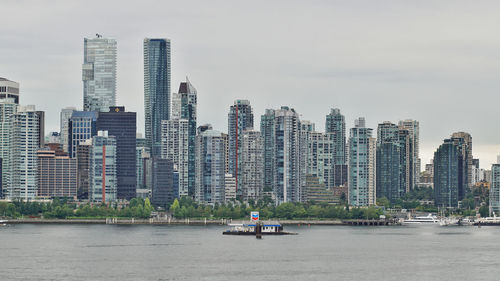 Modern buildings by river against sky in city