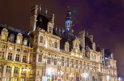 Low angle view of illuminated buildings against sky at night