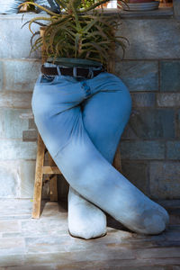 Low section of person sitting on chair against wall