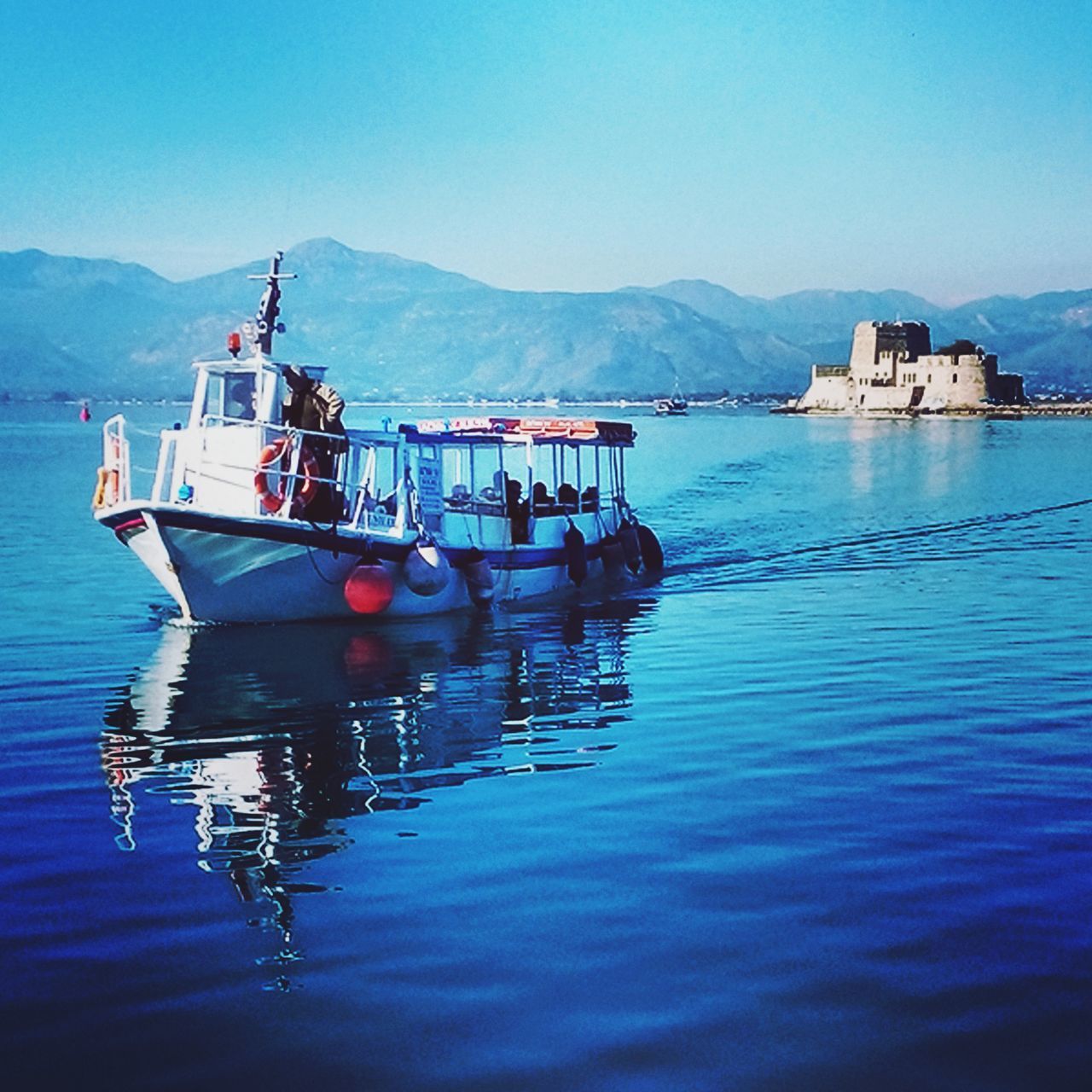 water, mountain, nautical vessel, transportation, boat, mode of transport, waterfront, moored, clear sky, reflection, mountain range, blue, tranquility, lake, tranquil scene, scenics, sea, nature, beauty in nature, sky