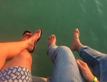 Low section of people sitting by lake