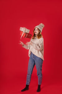 Portrait of a smiling young woman against red background