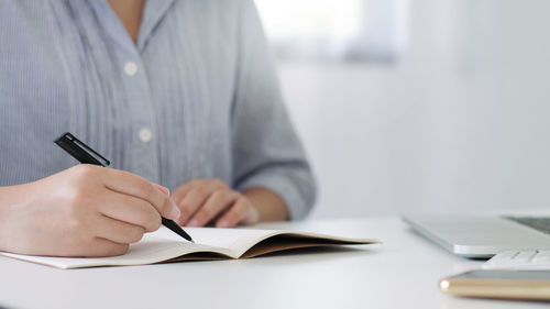 Midsection of man reading book on table