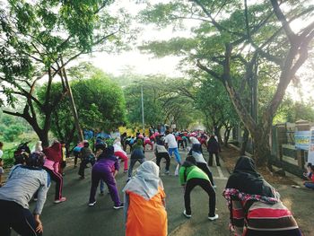 Rear view of people walking on road amidst trees