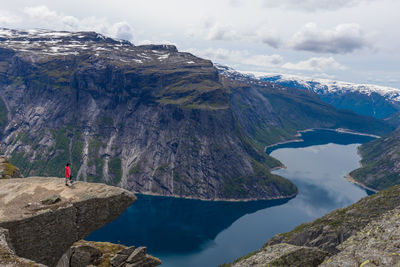 Woman standing on edge of cliff at trolltunga mountain in norway.