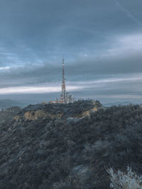 Low angle view of communications tower against cloudy sky