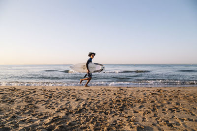 Man riding on beach against clear sky
