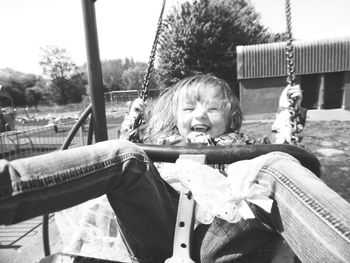 Smiling girl playing on swing at park
