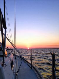 Suspension bridge over sea against clear sky during sunset