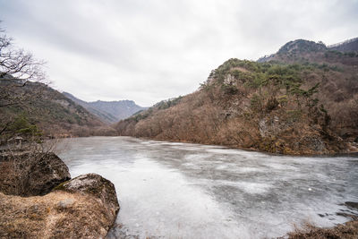 Scenic view of river by mountains against sky