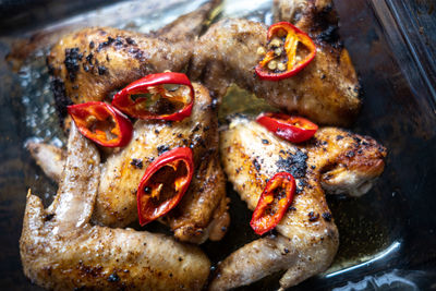 High angle view of organic pasture-raised chicken wings, grilled and garnished with chili pepper 