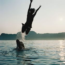 Man jumping in sea against sky