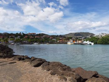 Scenic view of sea by townscape against sky