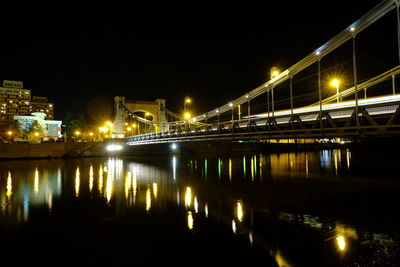 Illuminated bridge over river against sky at night